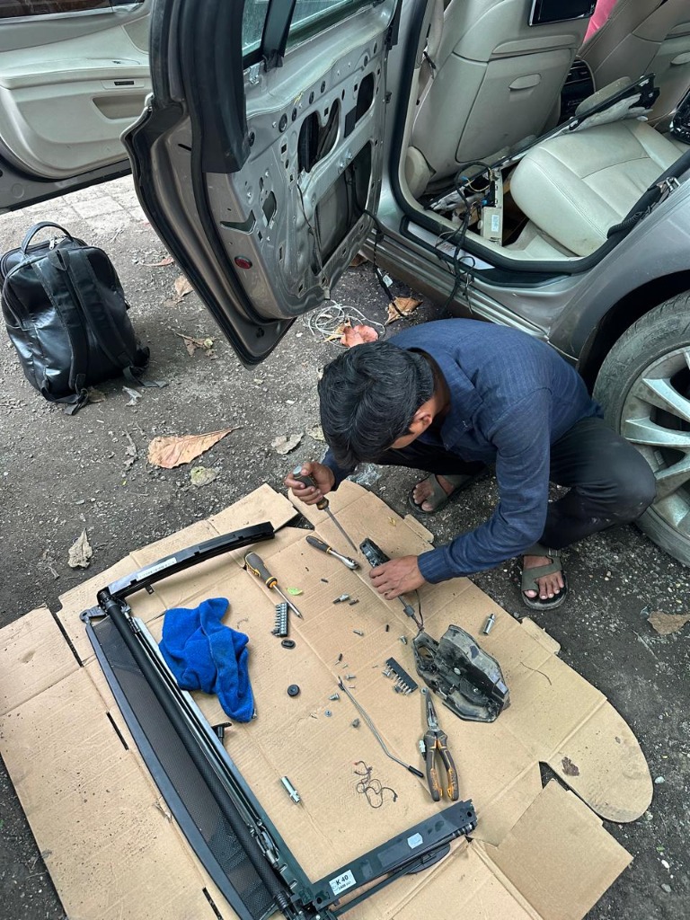 Technician working on a disassembled vehicle door and interior components